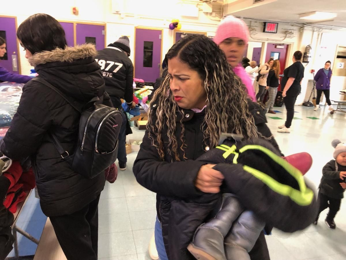 A woman is holding a baby in her arms while wearing a jacket with the number 1977 on it