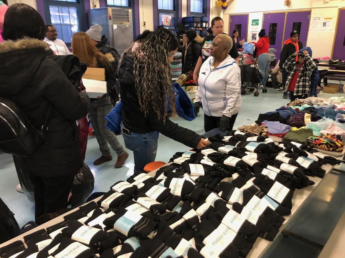A group of people are standing around a table with a lot of socks on it.