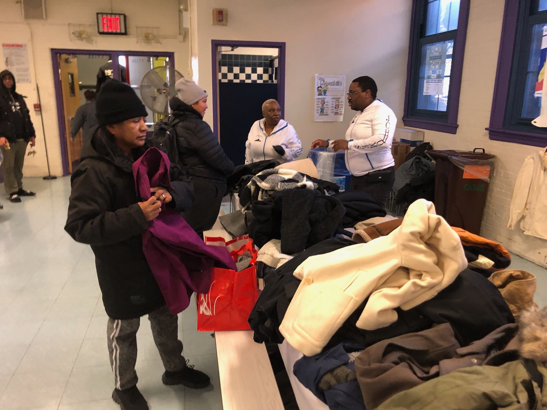 A group of people are standing around a table full of clothes.