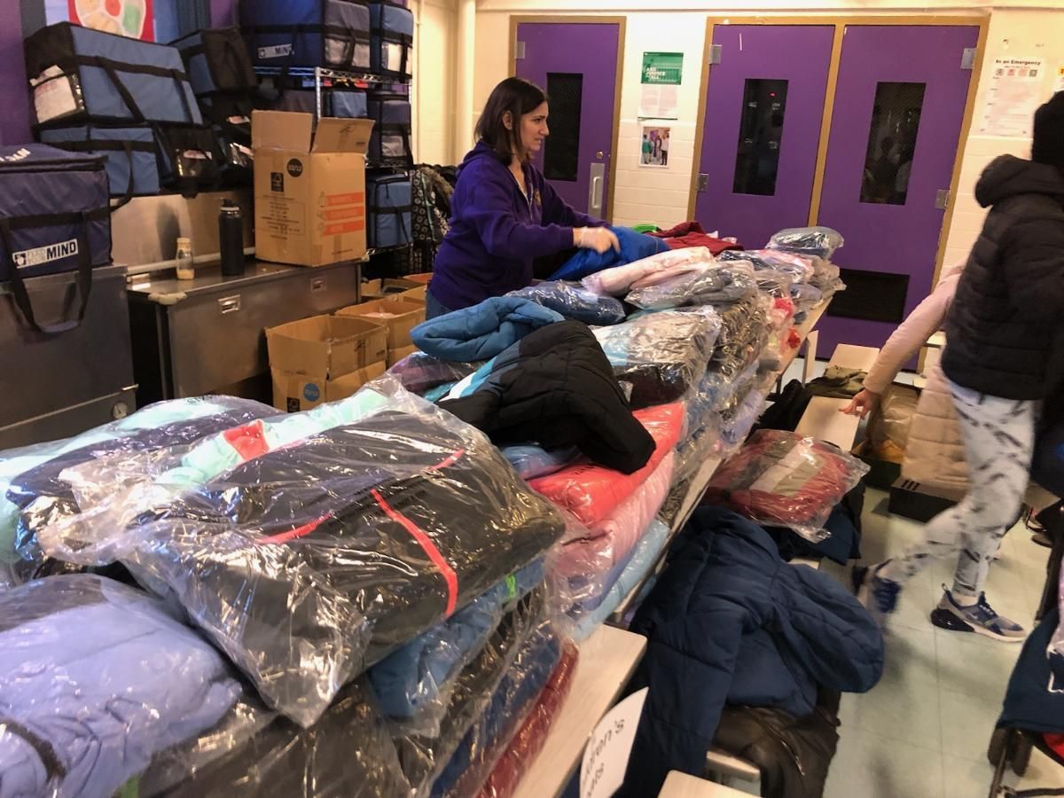 A woman is sorting clothes on a table in a room with purple doors.