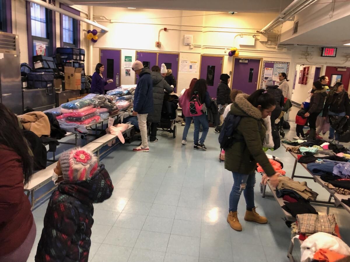 A group of people are standing in a room looking at clothes.