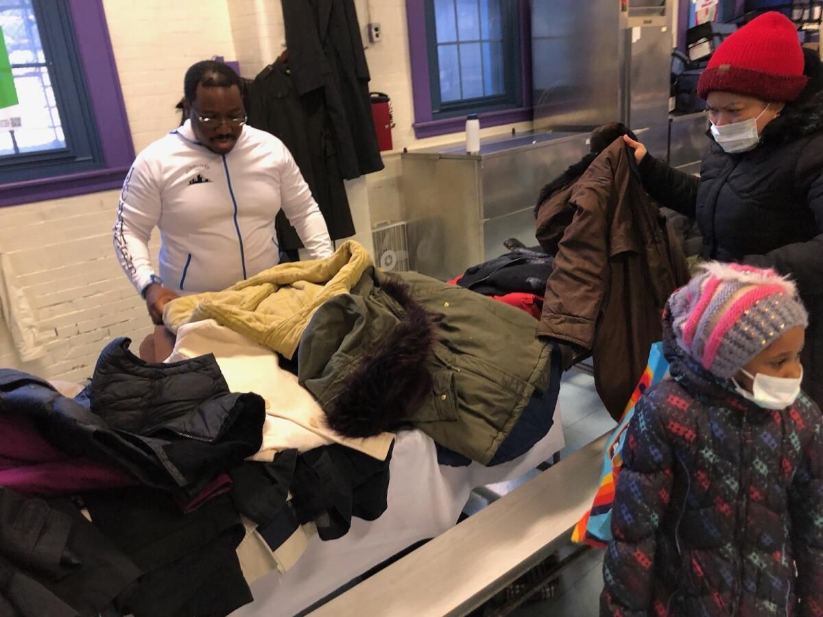 A group of people are standing around a table holding jackets.