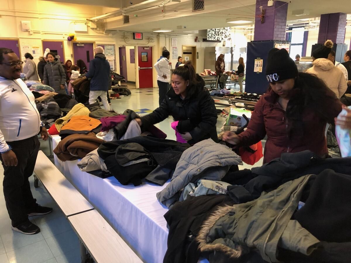 A group of people are standing around a table full of clothes.
