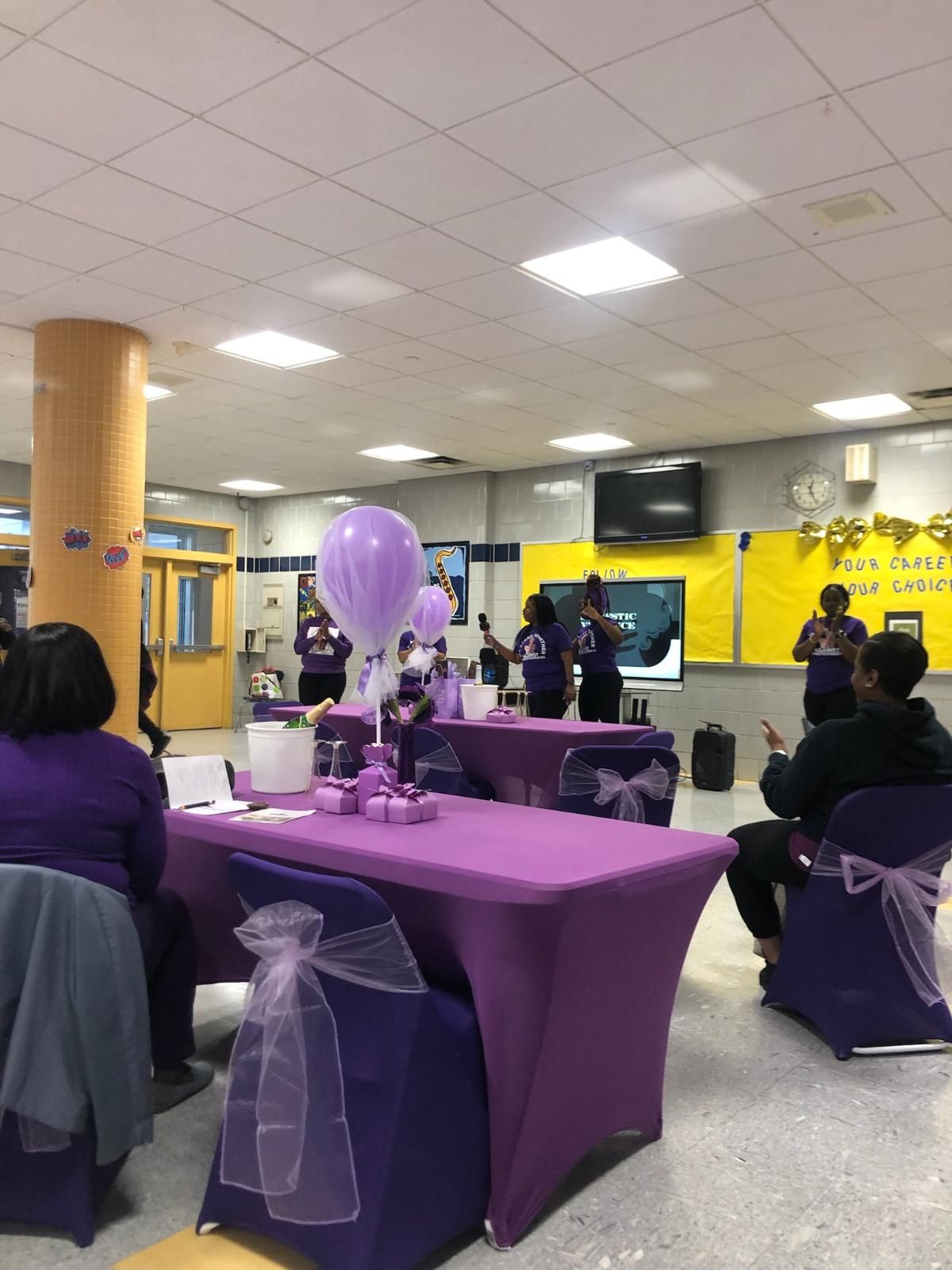 A group of people are sitting at purple tables in a room