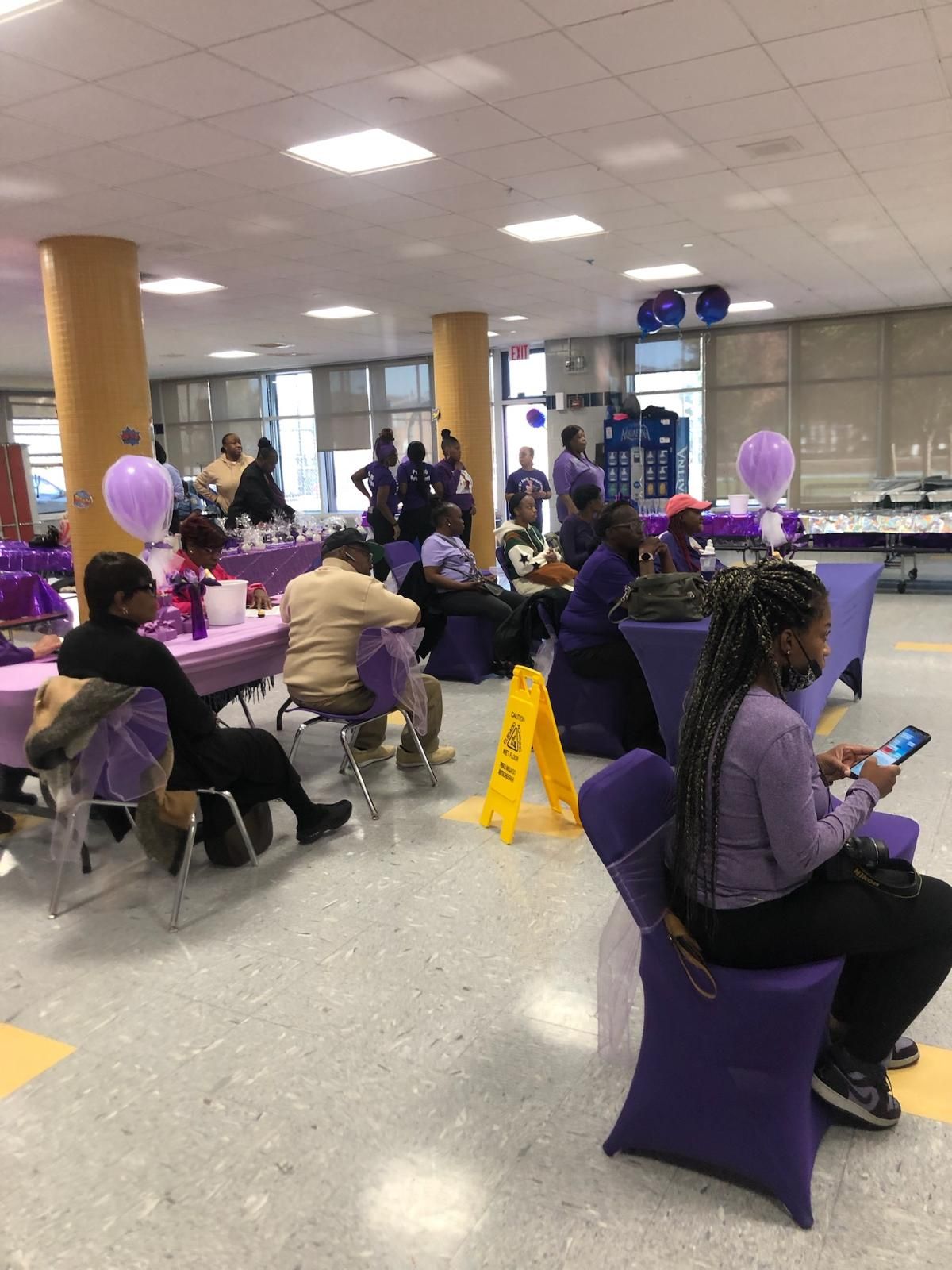 A group of people are sitting at tables and chairs in a room.