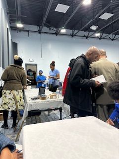 A group of people are standing around tables in a room.