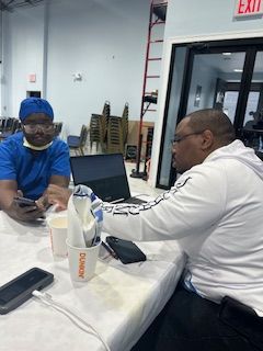 Two men are sitting at a table looking at their phones.