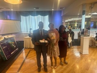 A man and two women are standing next to each other in a room.