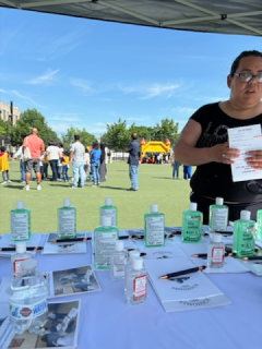 A woman stands behind a table with bottles of hand sanitizer on it