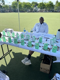 A man sits at a table with a lot of green cups on it
