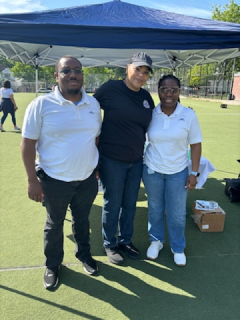 Three people are posing for a picture under a blue tent.