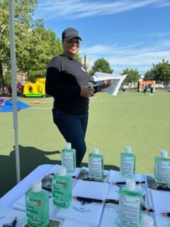 A woman standing next to a table with bottles of hand sanitizer on it