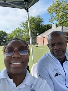 A man and a woman are sitting under a tent on a soccer field.