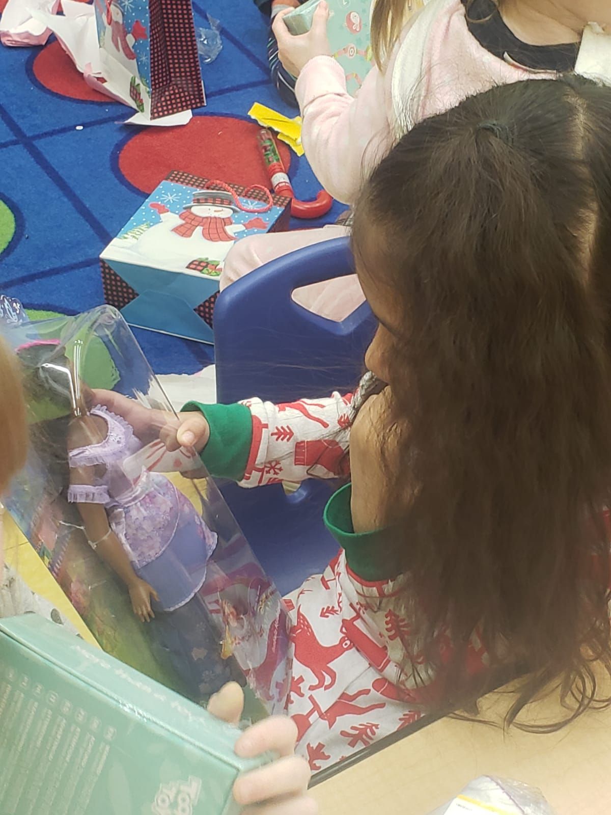A little girl is playing with a doll in a box.