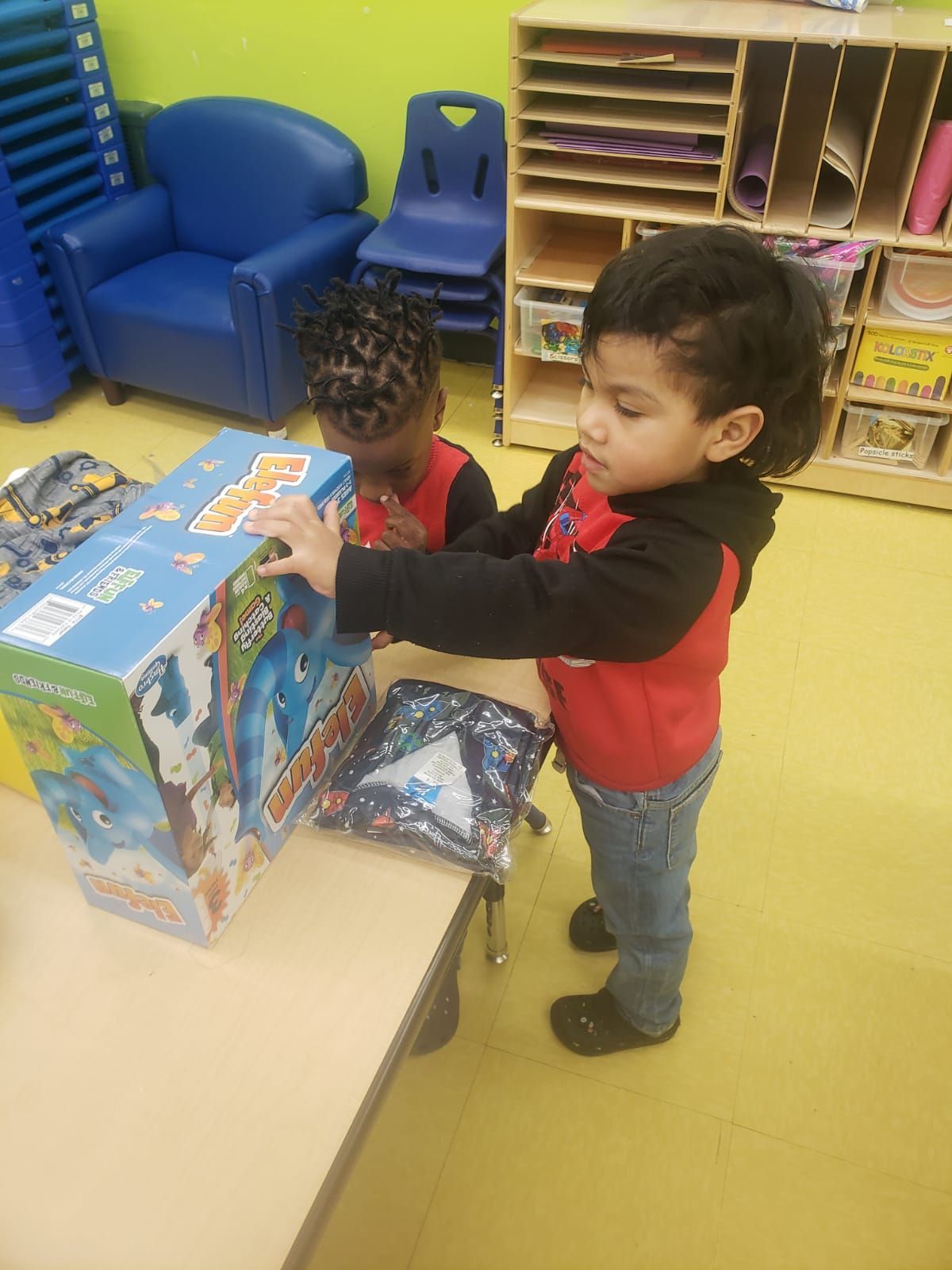 Two young children are playing with toys in a classroom.