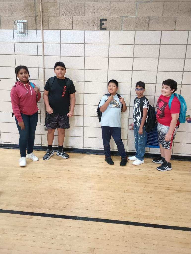 A group of children are standing next to each other in front of a brick wall.