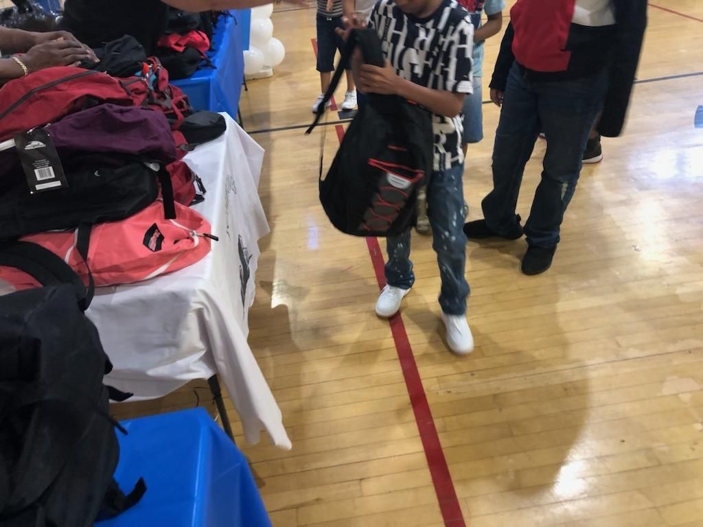 A group of people are standing around a table with backpacks on it.