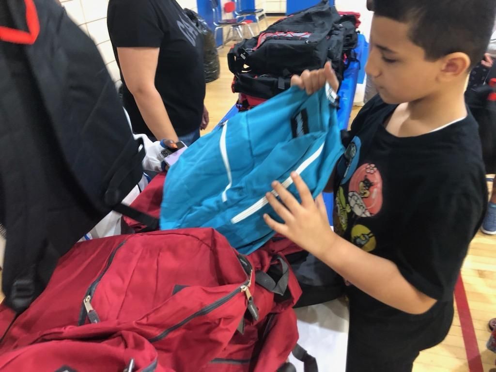A young boy is looking at a blue backpack in a store.