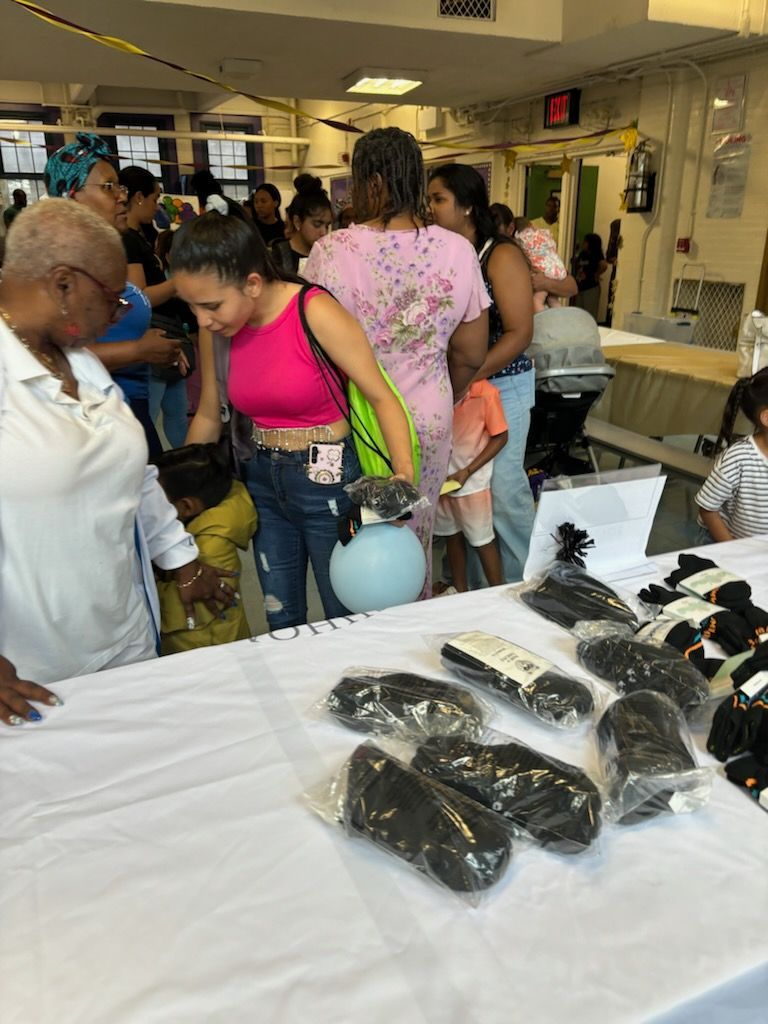 A group of people are standing around a table looking at hair extensions.
