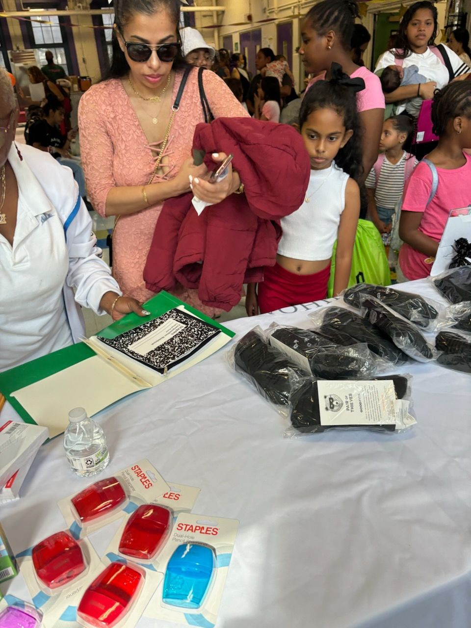 A group of people are standing around a table looking at items.