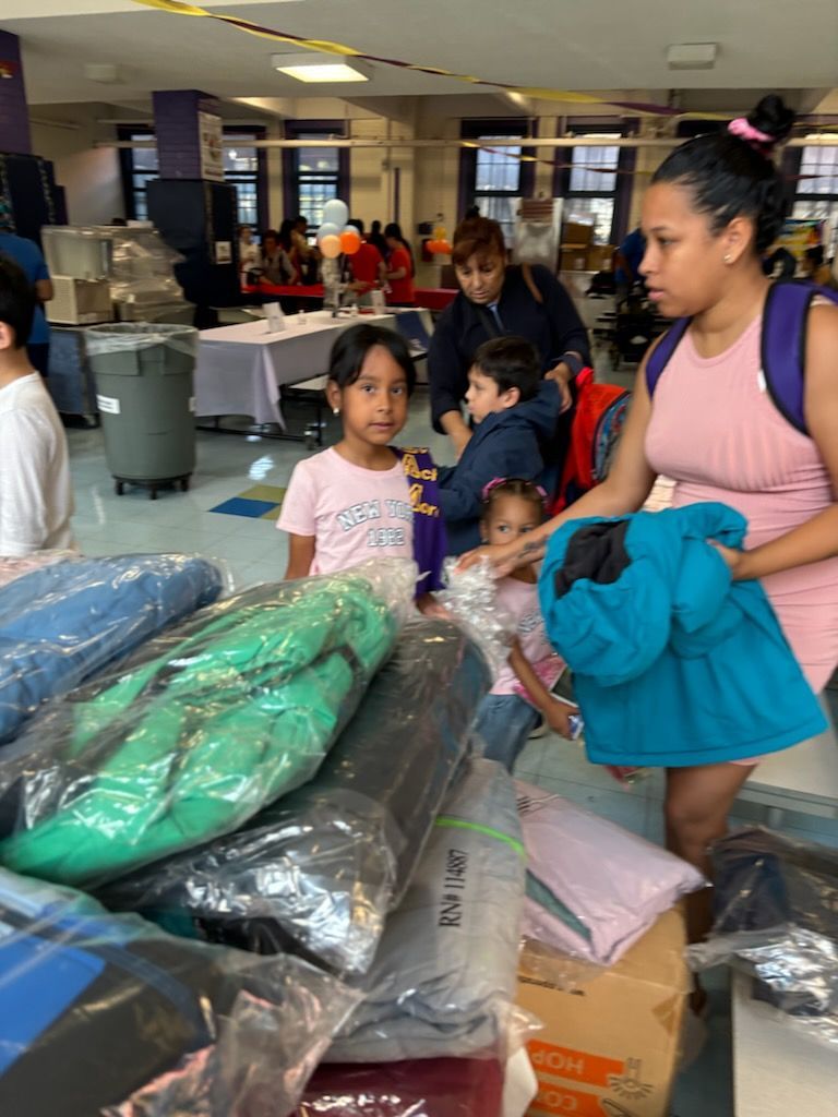A woman and two children are standing in front of a pile of clothes.