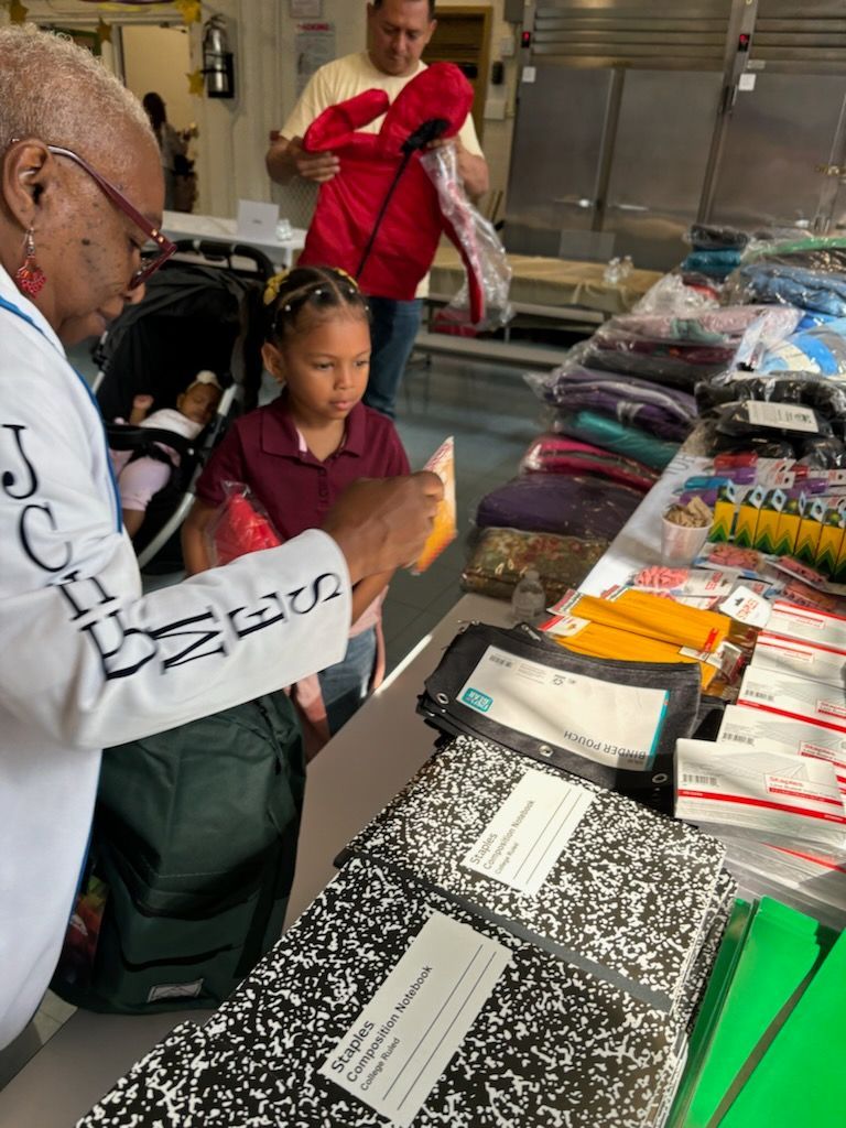 A man and a little girl are looking at a table full of school supplies.