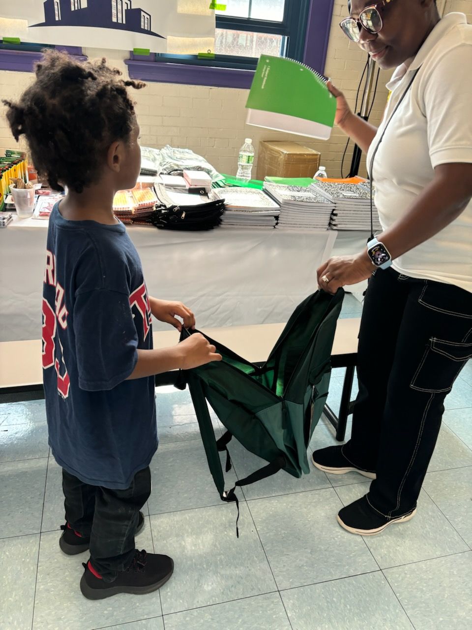 A woman is helping a young boy pack his backpack