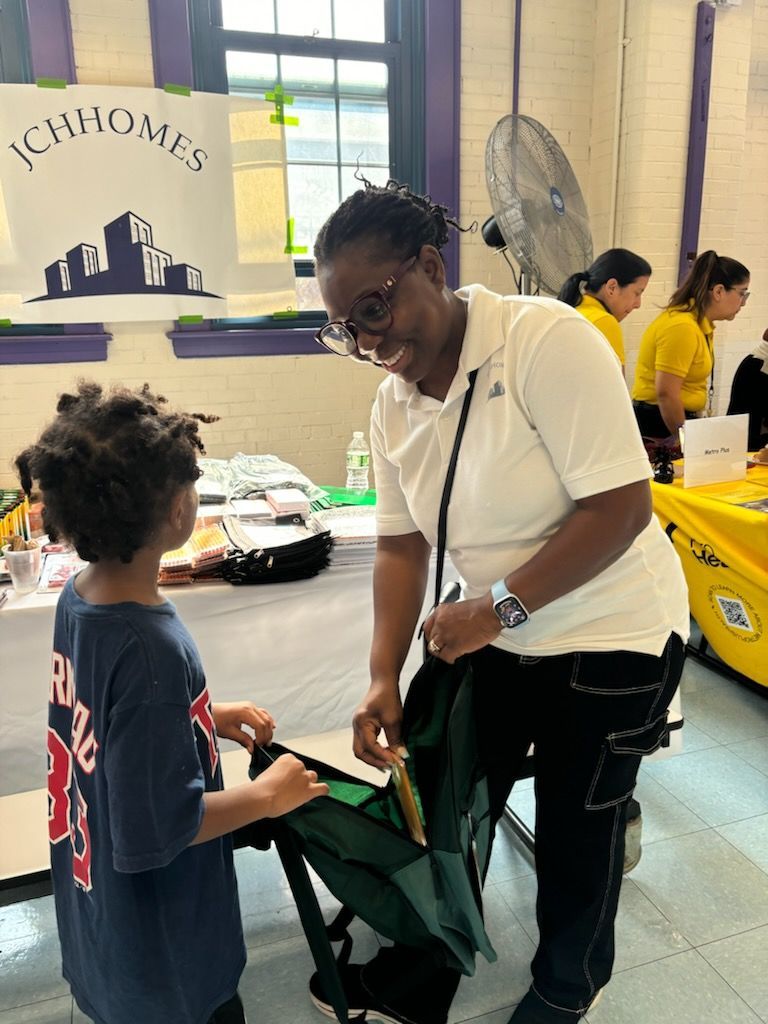 A woman is helping a young boy with his backpack.