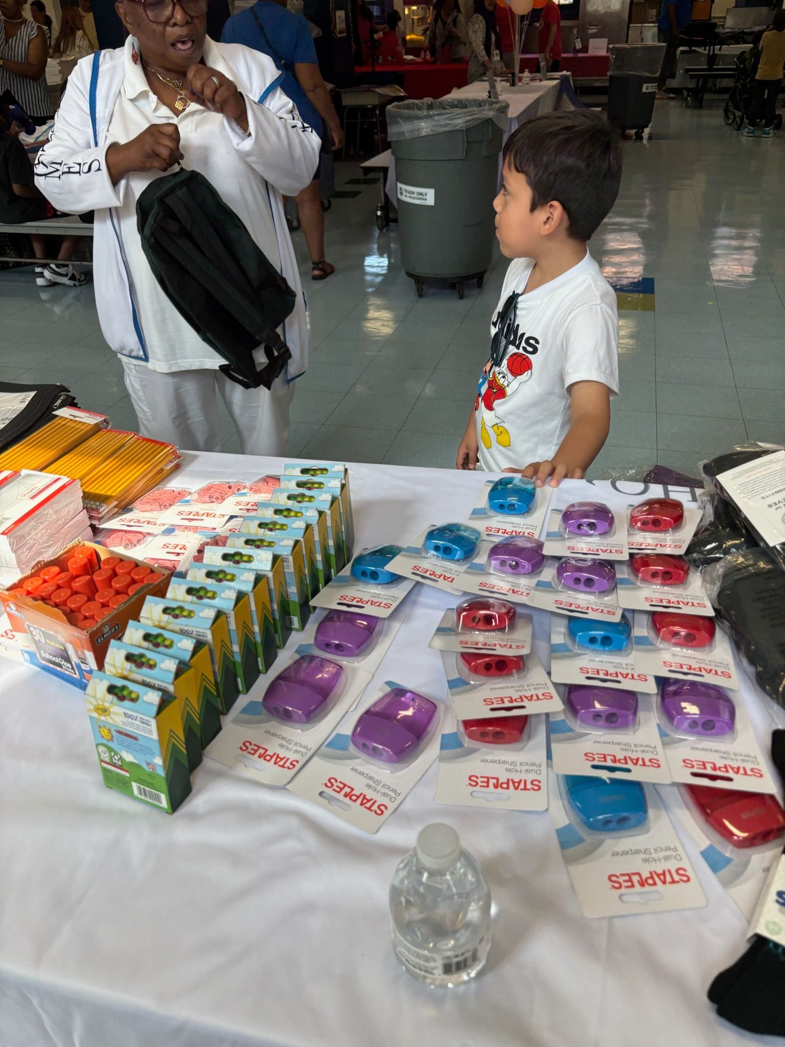 A little boy is standing in front of a table filled with lots of toys.