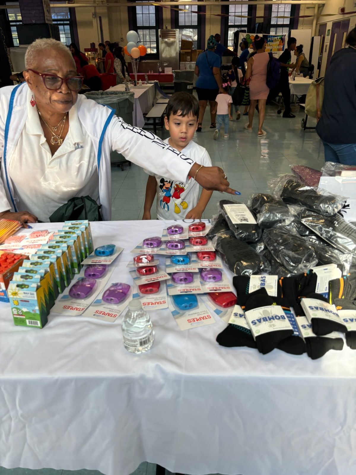 A woman and a boy are standing at a table selling socks.