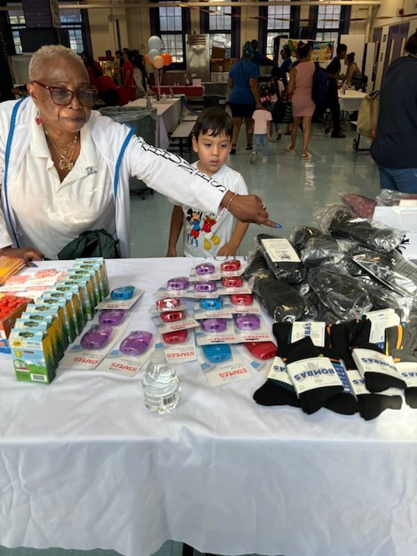 An elderly woman and a young boy are standing at a table selling socks.
