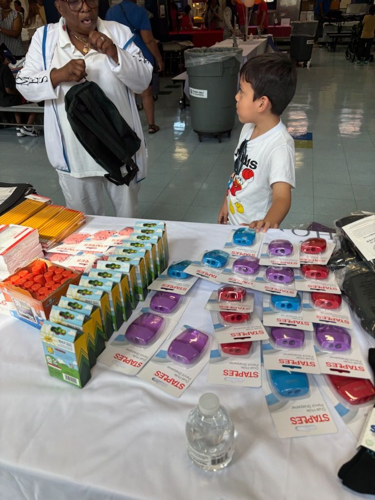 A little boy is standing in front of a table filled with lots of toys.
