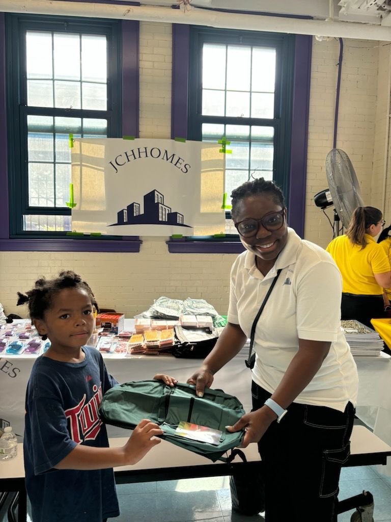 A woman is giving a backpack to a young boy.