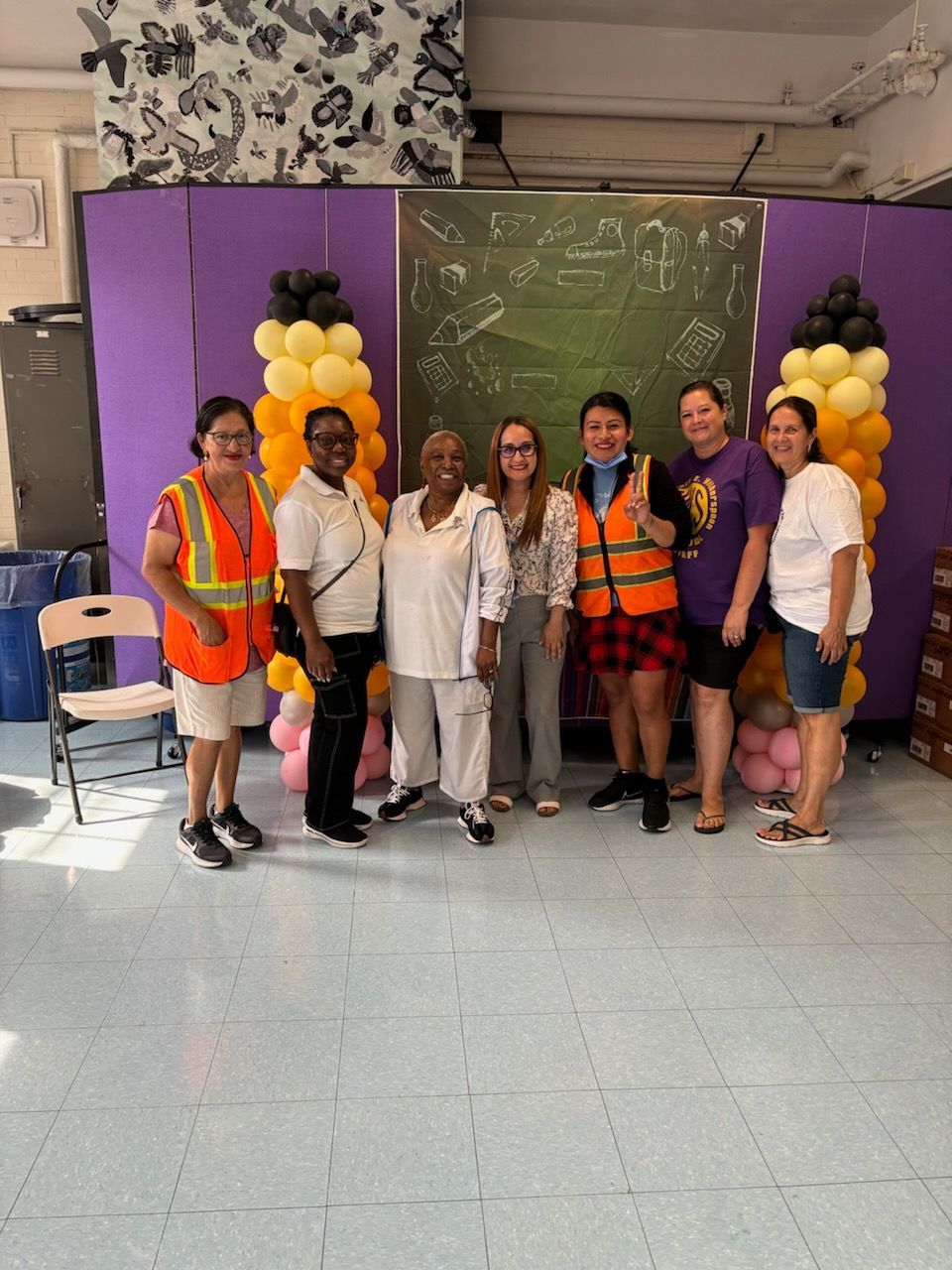 A group of people are posing for a picture in a room with balloons.