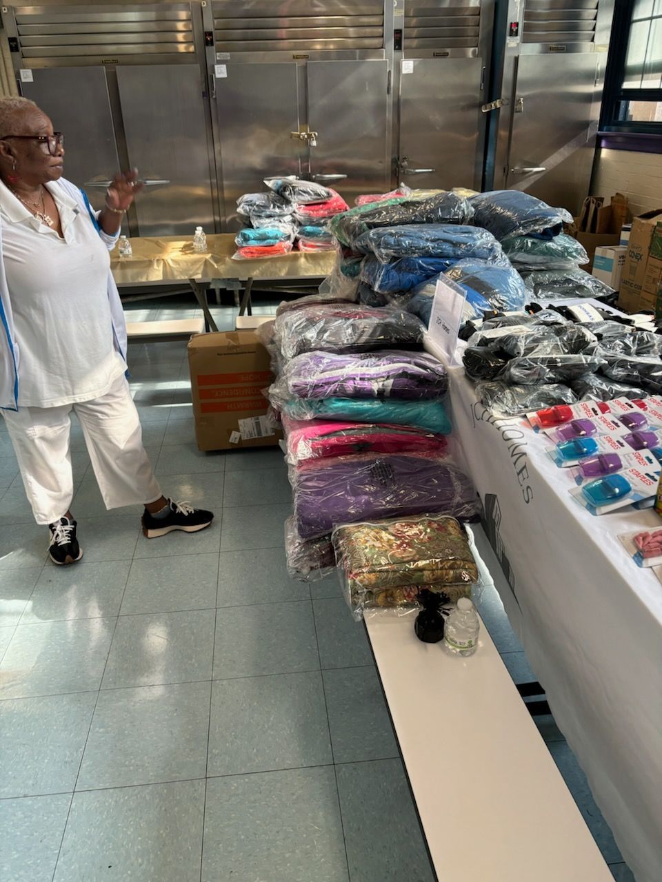 A woman is standing in front of a table full of clothes.