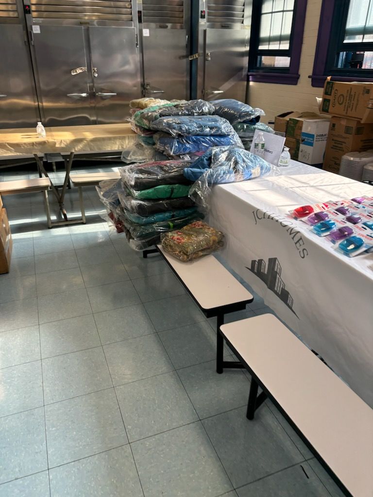 A room with a table and benches and a stack of clothes on it.