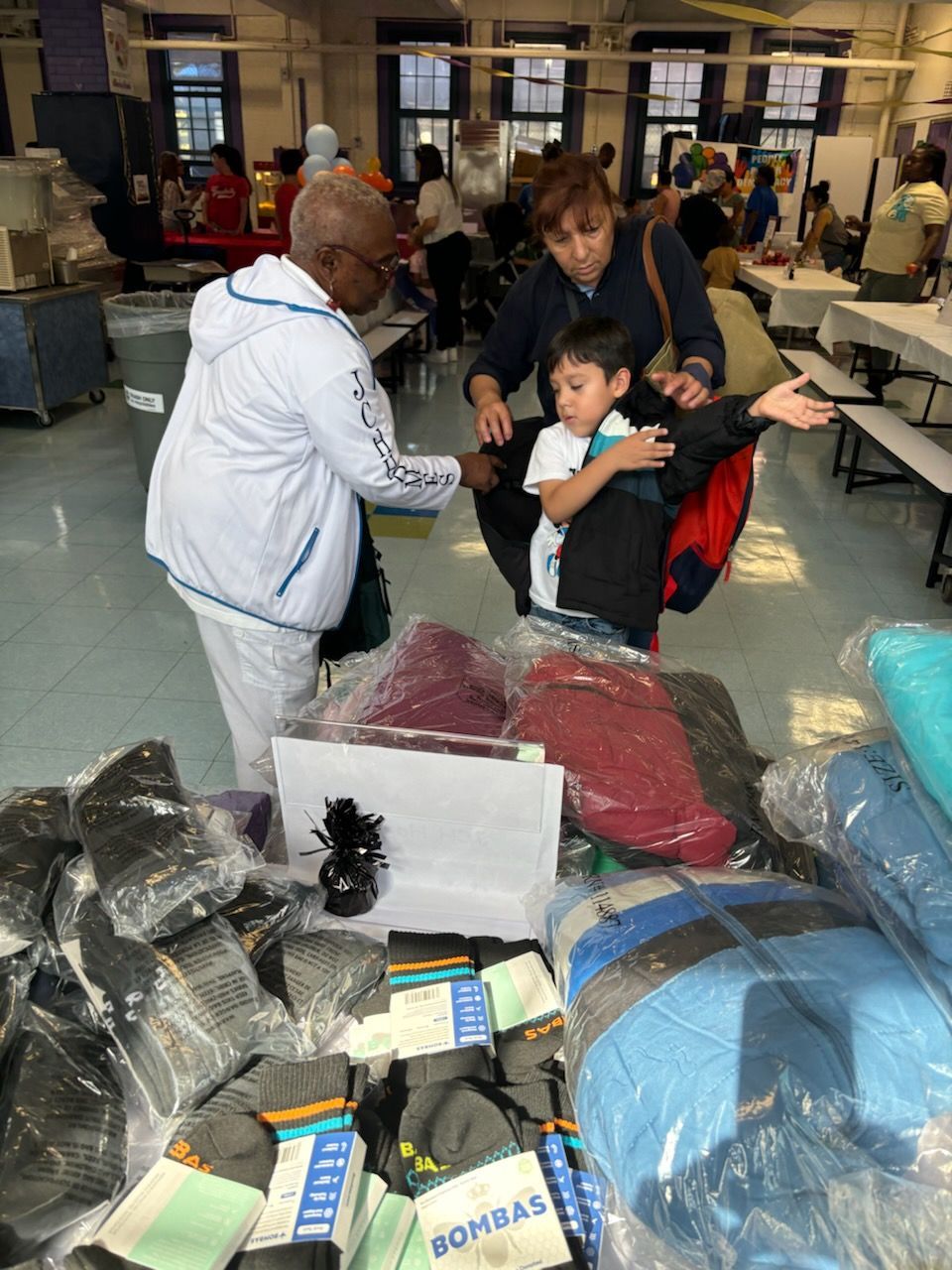 A group of people are standing around a table looking at clothes.