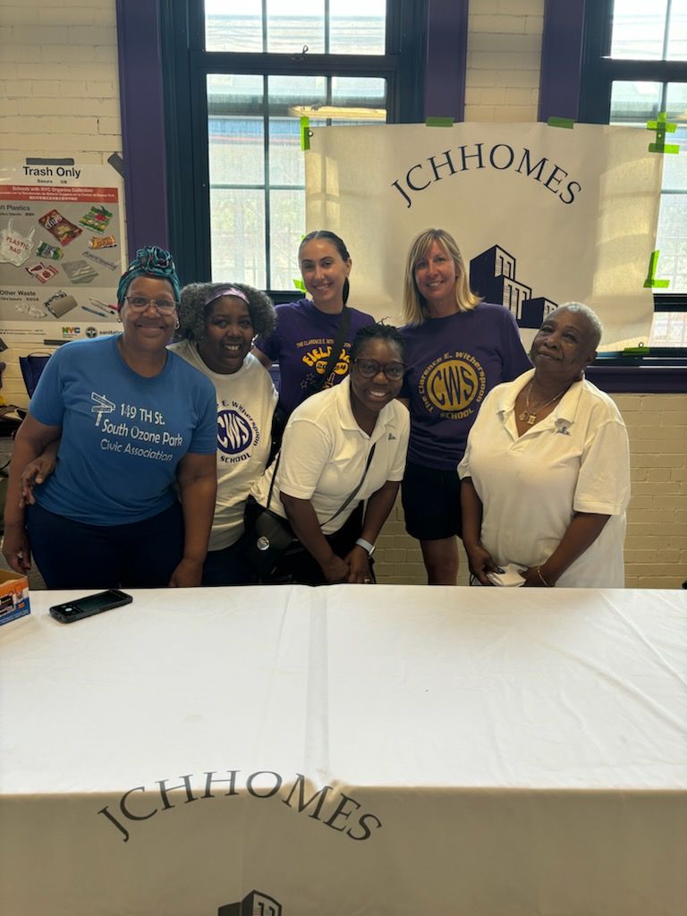 A group of women are posing for a picture in front of a table.