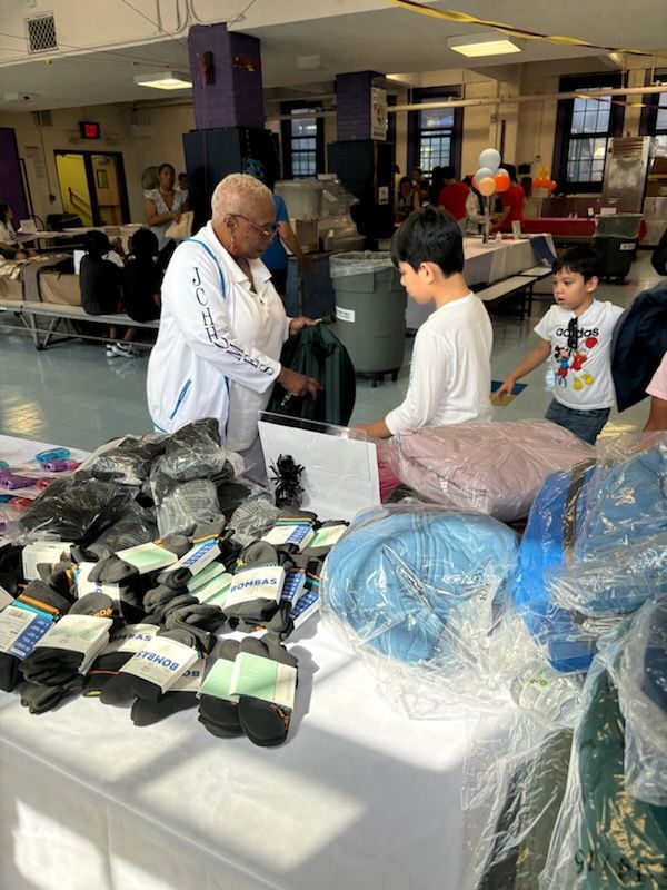 A man is standing in front of a table full of clothes.