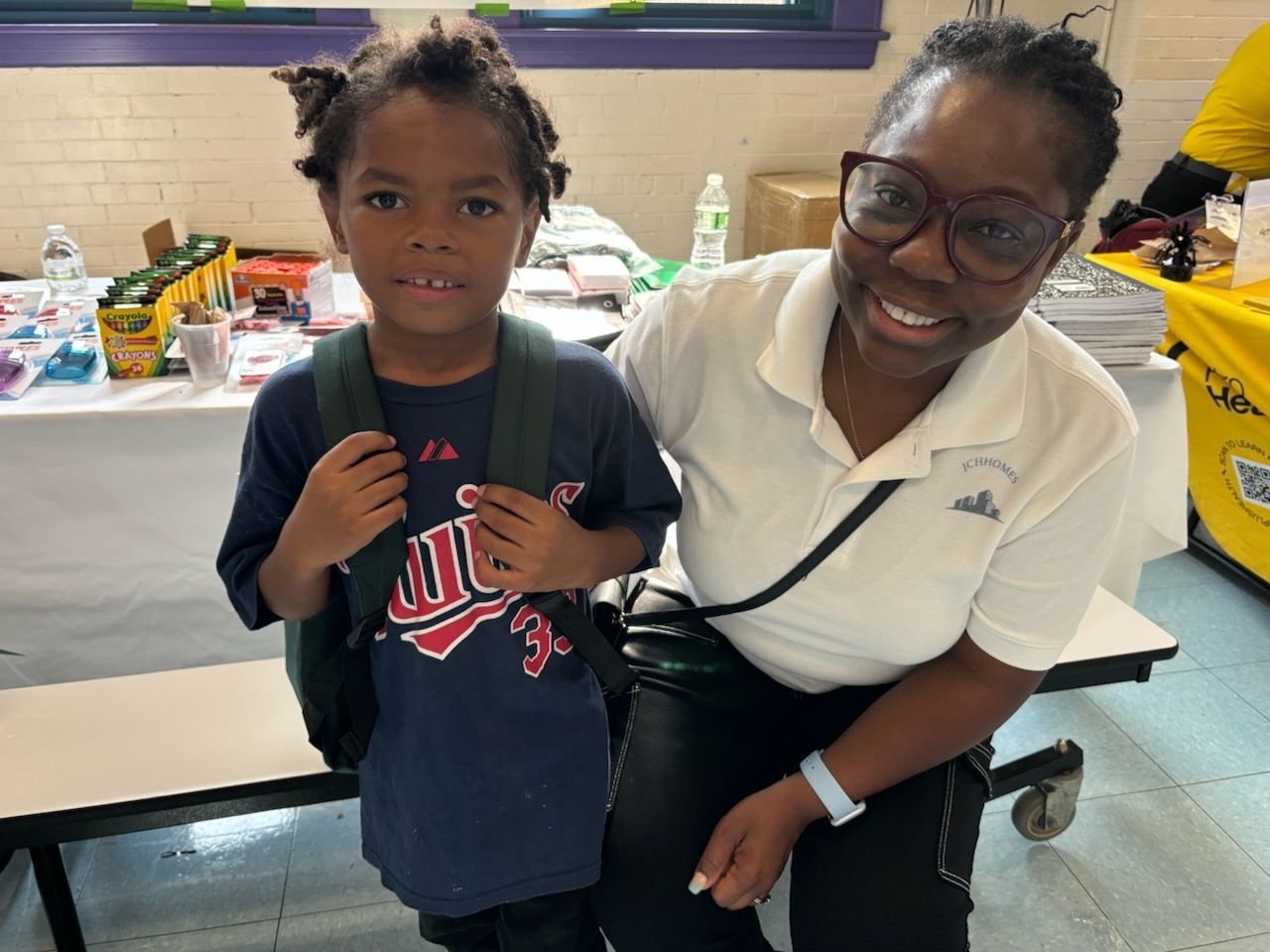 A woman is kneeling down next to a young boy wearing a nike shirt