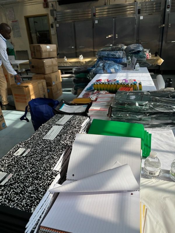 A man is standing behind a table filled with notebooks and boxes.