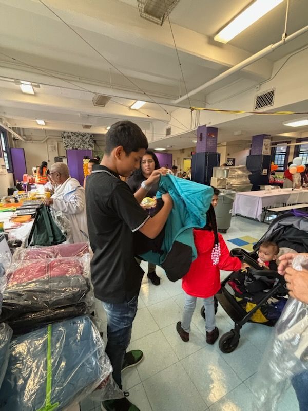 A group of people are standing in a room looking at clothes.