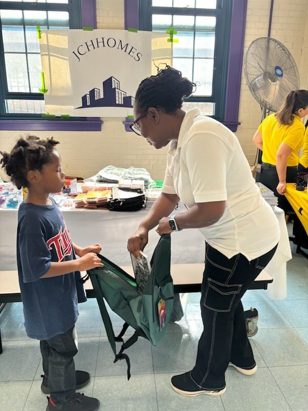 A woman is helping a young boy pack his backpack
