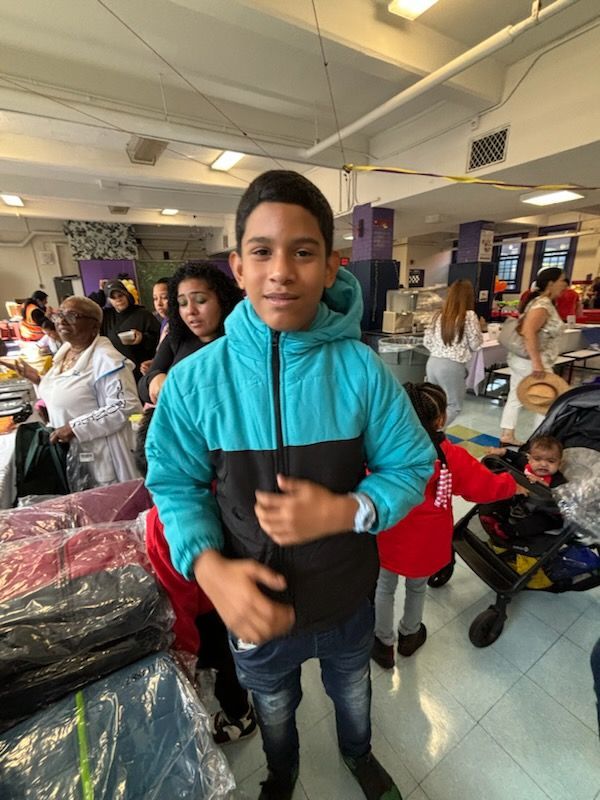 A boy in a blue jacket is standing in a crowded room.