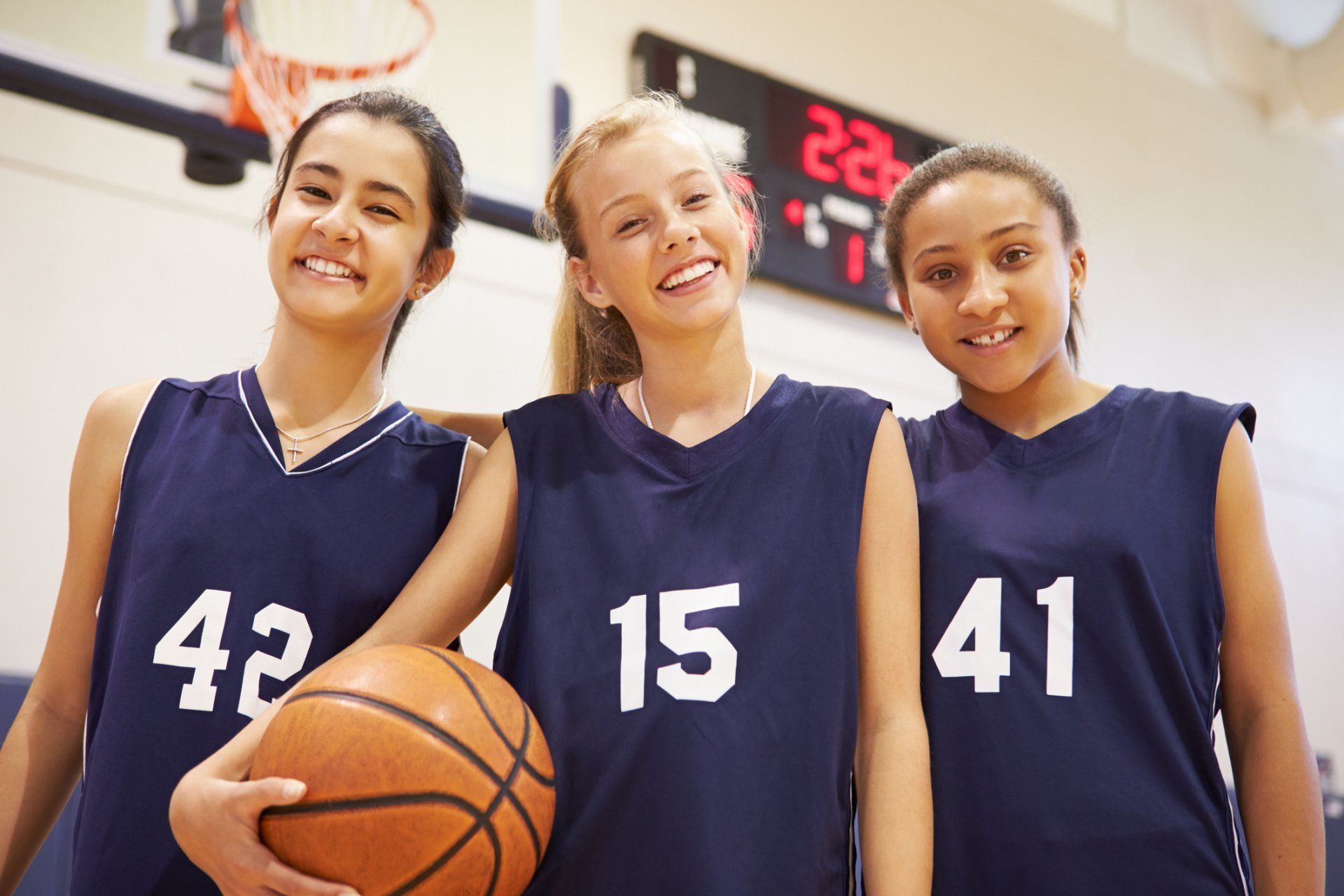 Three female basketball players wearing uniforms with the numbers 42 15 and 41 holding a basketball