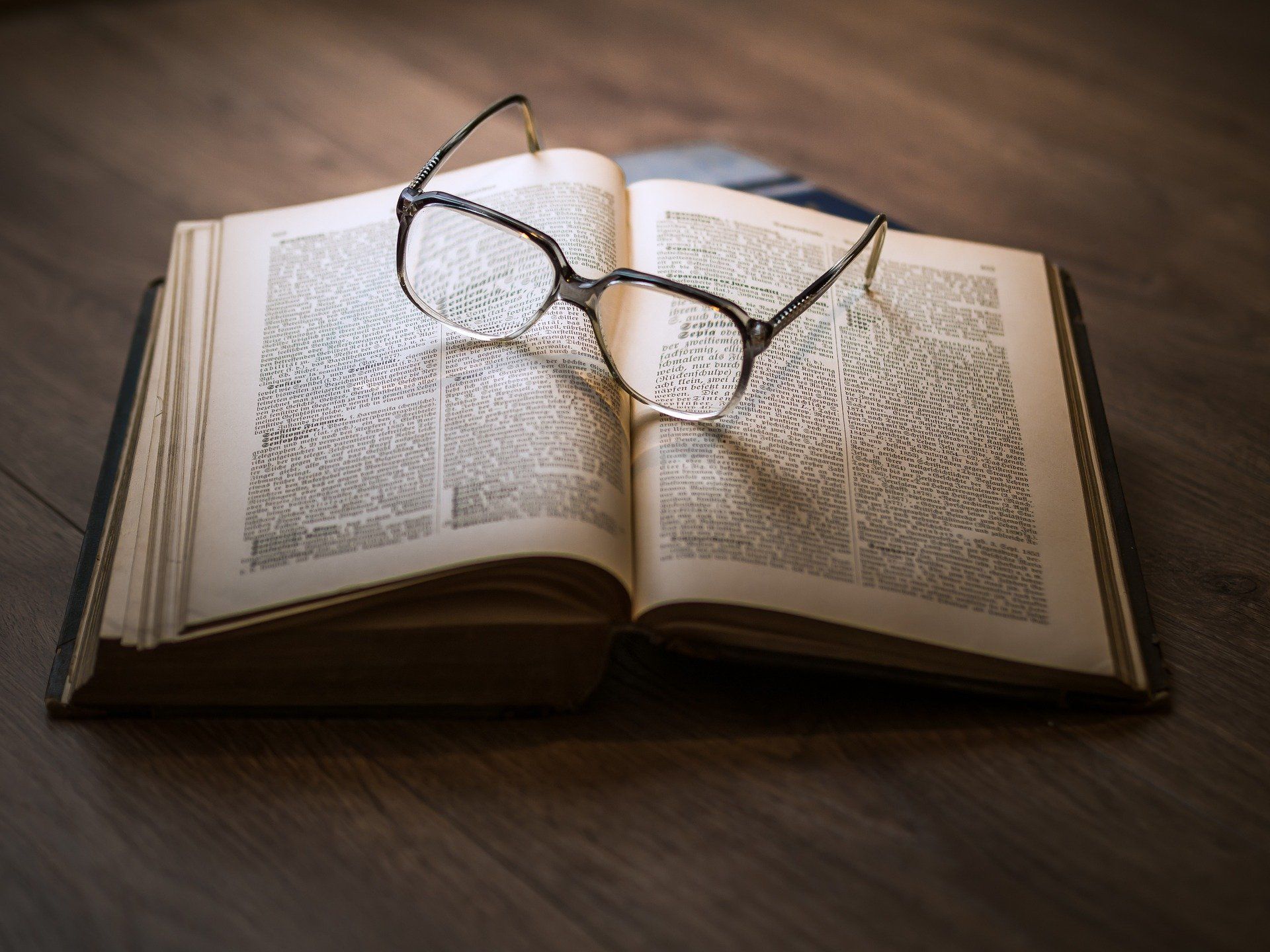 A pair of glasses is sitting on top of an open book.