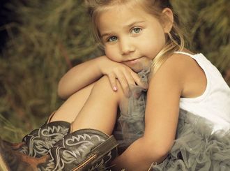 A little girl is wearing cowboy boots