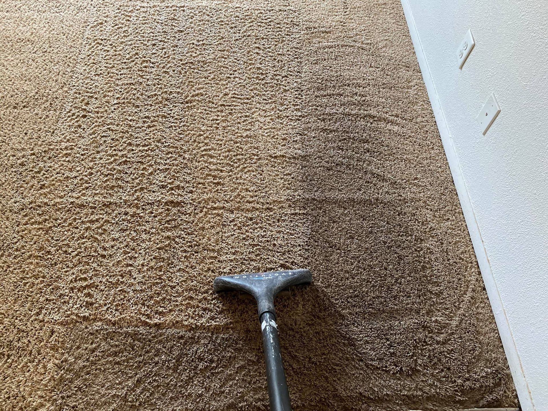 a vacuum cleaner is cleaning a brown carpet .