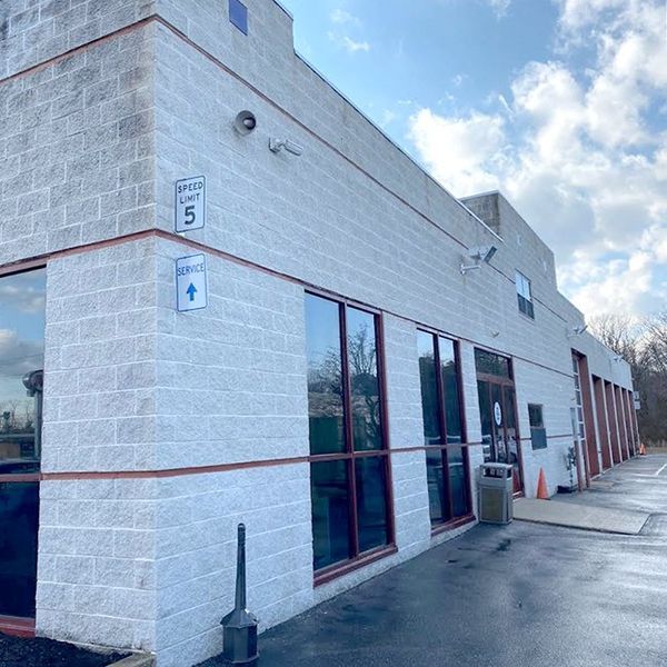 Exterior of a light-colored commercial building with large windows and a speed limit sign.