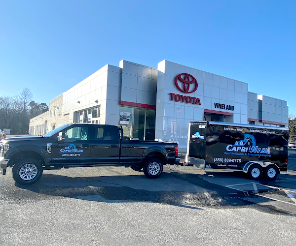 Dark truck with trailer in front of a Toyota dealership, both branded 